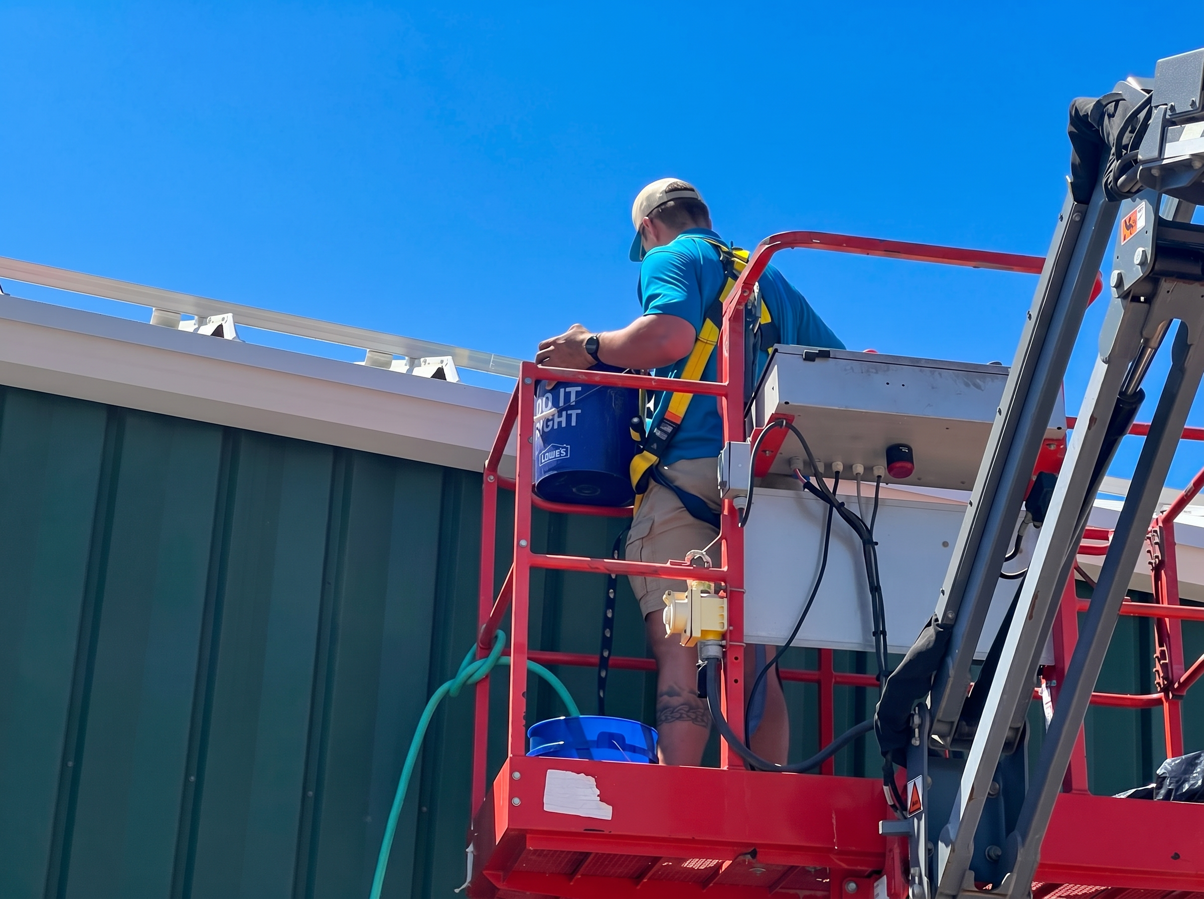 Sioux Falls Commercial Cleaning technician on a scissor lift cleaning the exterior gutters and roofline of a commercial building