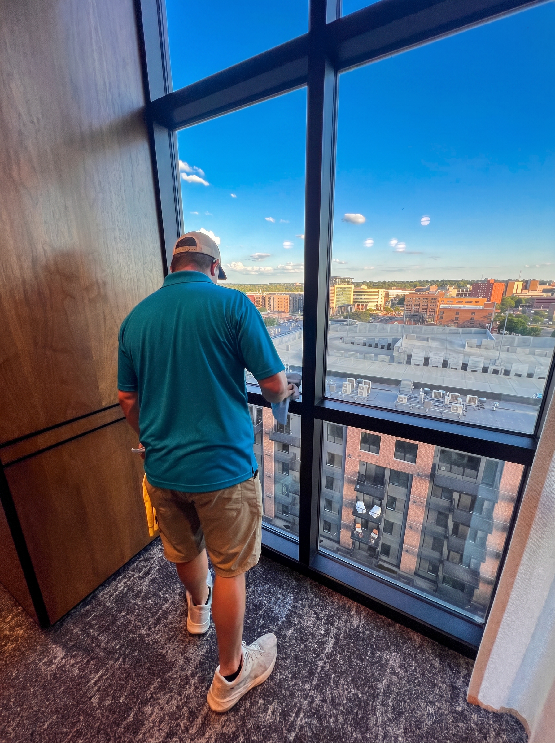Sioux Falls Commercial Cleaning technician cleaning a high-rise interior window overlooking downtown Sioux Falls
